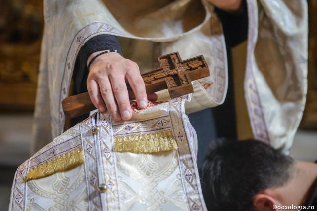 preot cu crucea în mână pe capul unui credincios