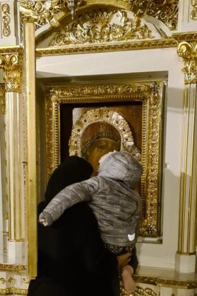 maică atingând un copil de icoana Maicii Domnului