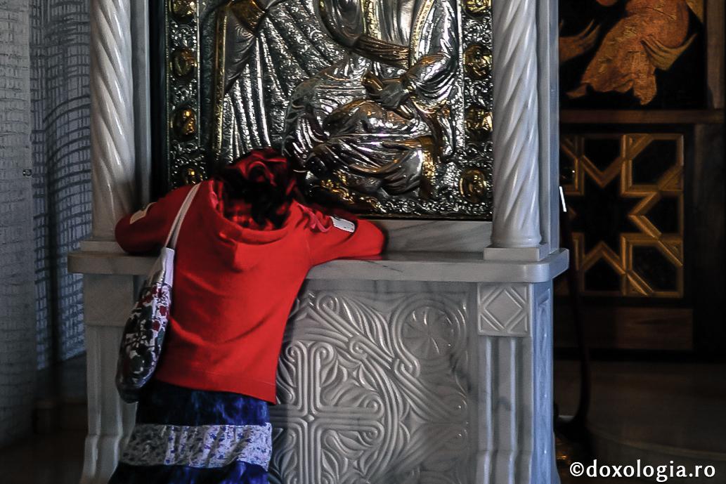 femeie în fața icoanei Maicii Domnului