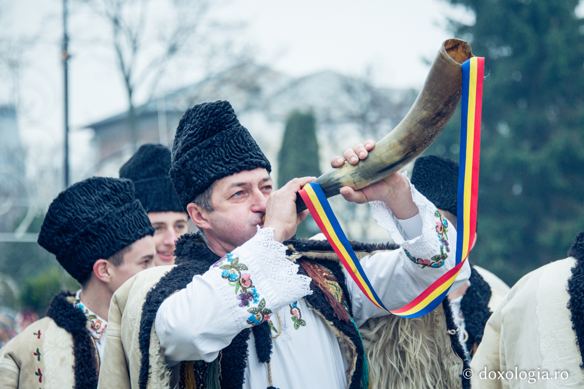 bărbat în costum popular suflând în corn