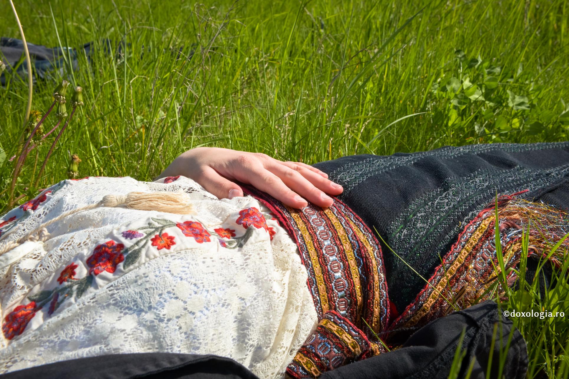 femeie în costum popular stând în iarbă