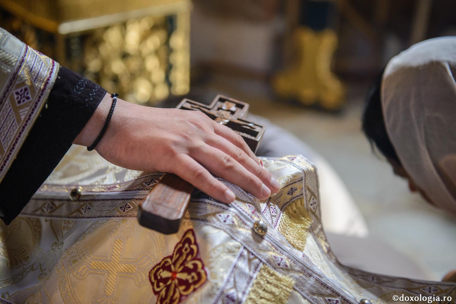 preot cu crucea în mână pe capul unui credincios