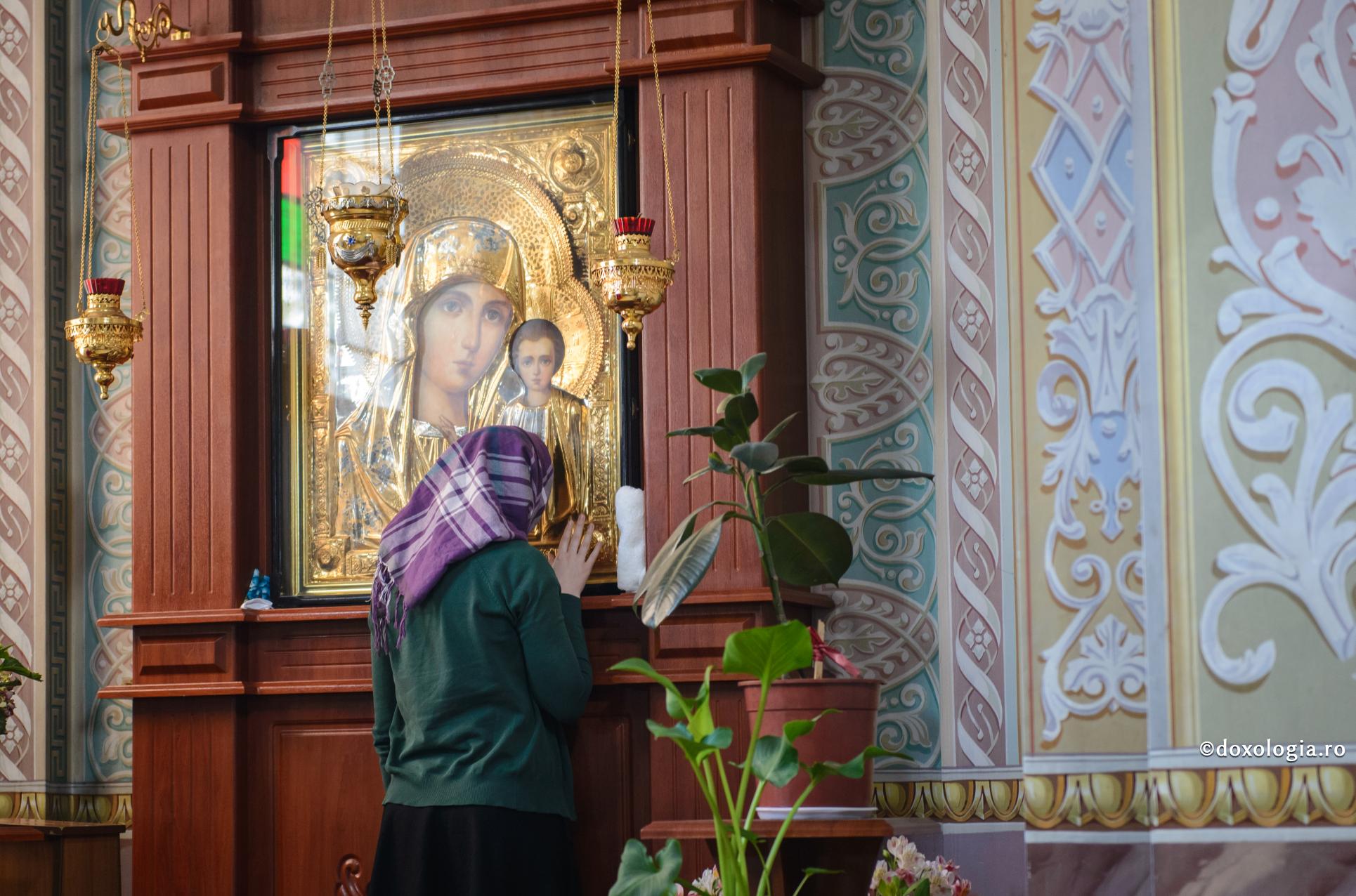 femeie în fața icoanei Maicii Domnului