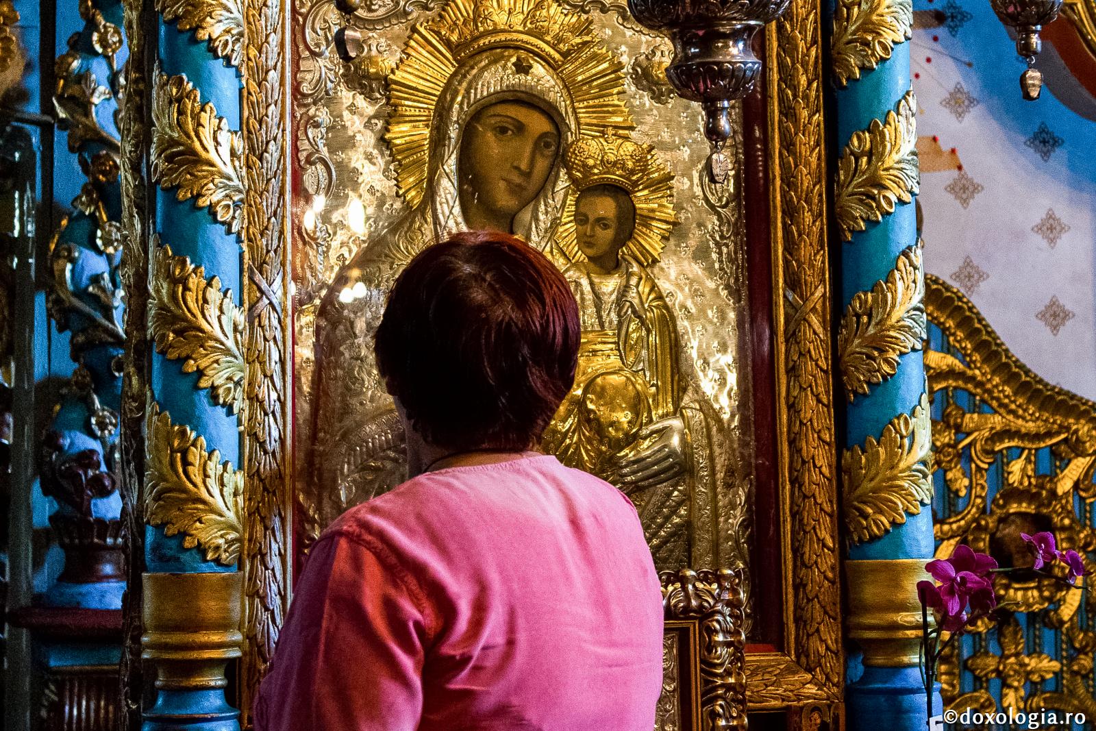 femeie în fața icoanei Maicii Domnului