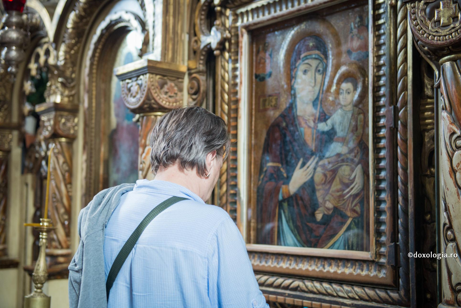 femeie în fața icoane Maicii Domnului