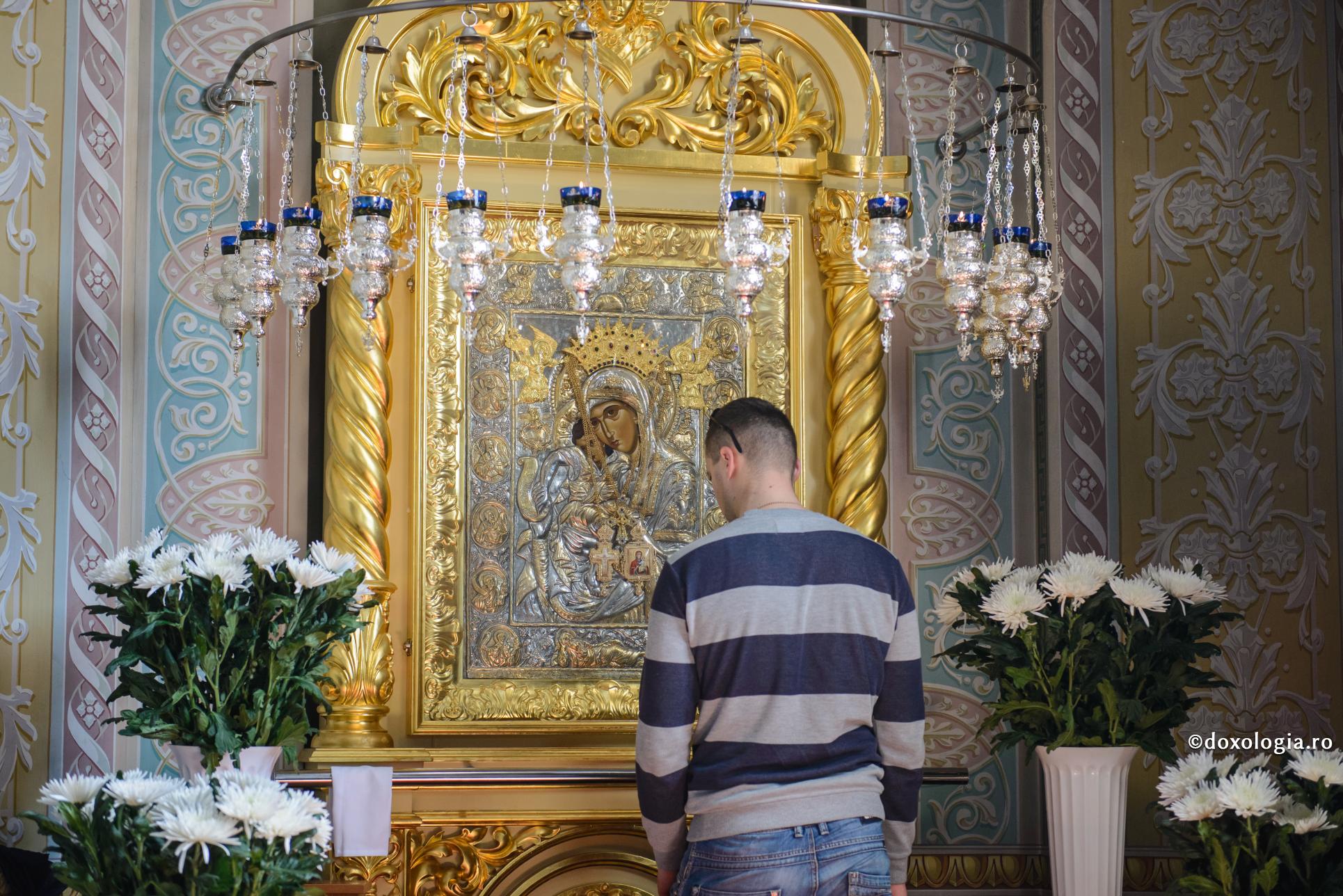 bărbat în fața icoanei Maicii Domnului