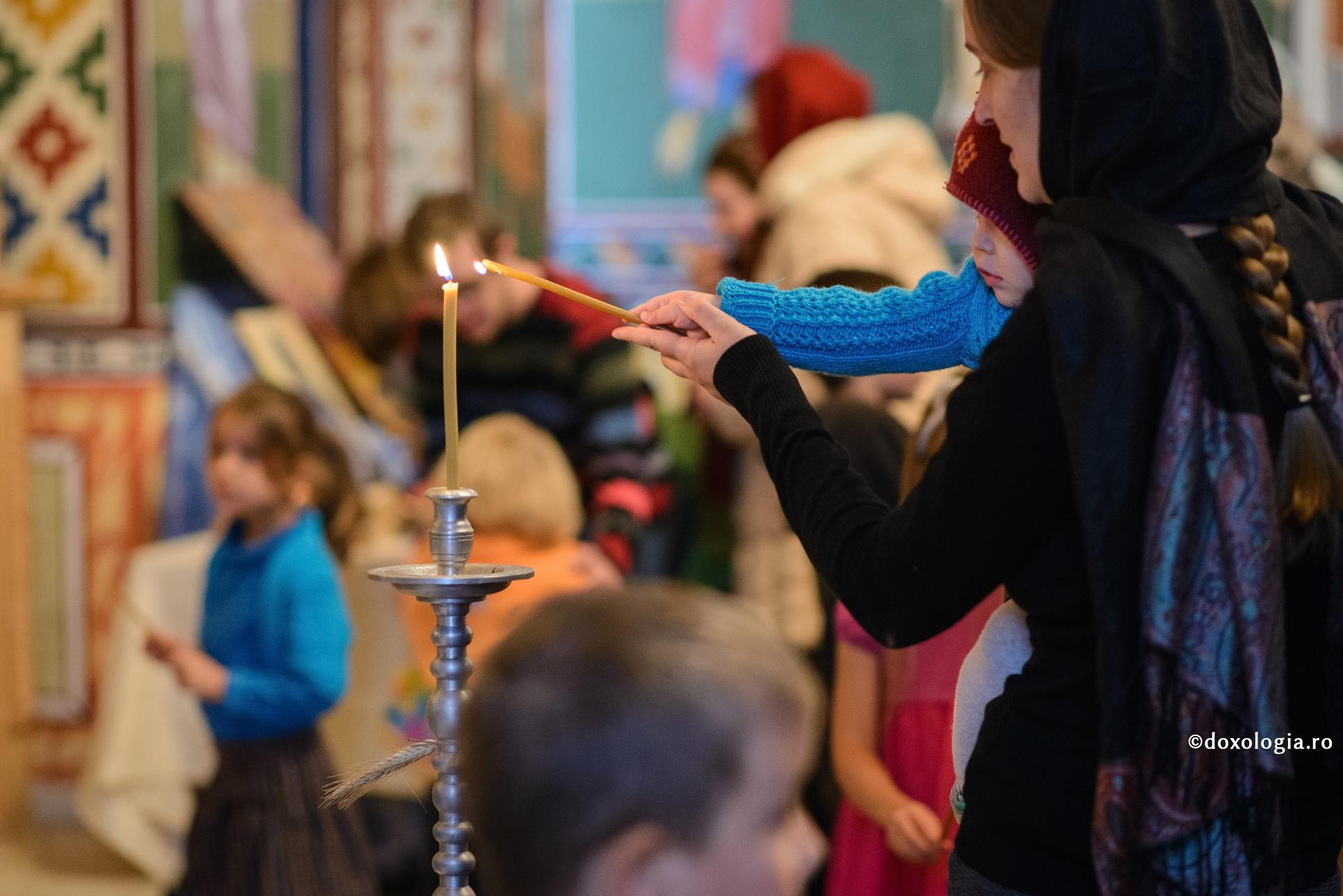 Părinții trebuie să-și țină în brațe copiii la Liturghie! / Foto: Oana Nechifor mama și copilul aprinzând lumânarea
