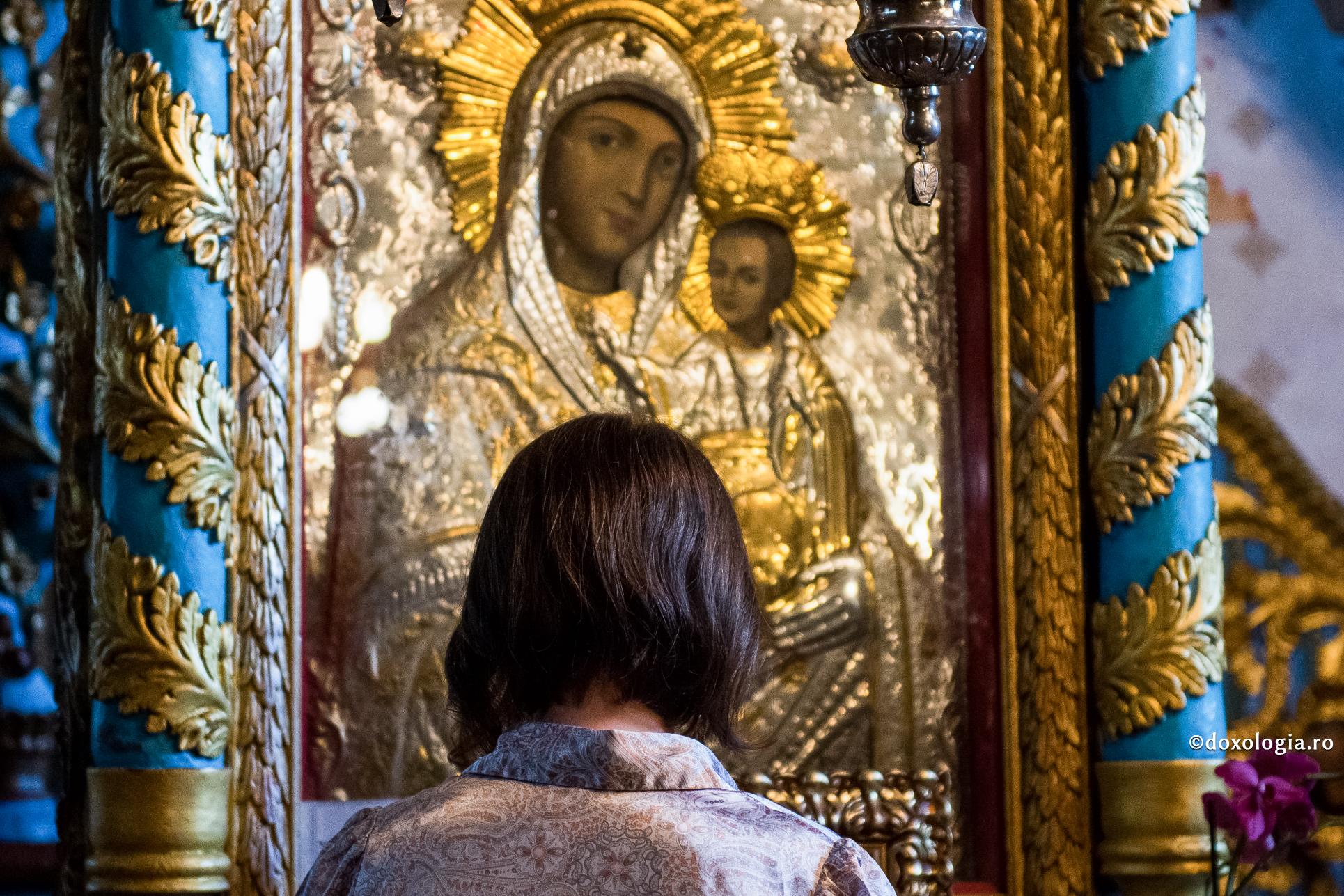 femeie în fața icoanei Maicii Domnului