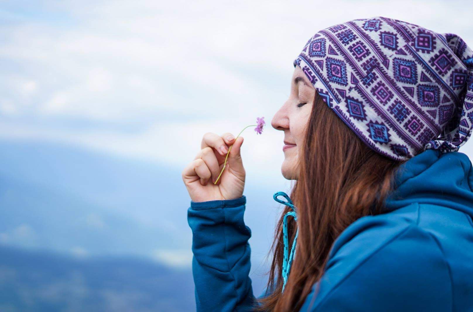 femeie mirosind o floare