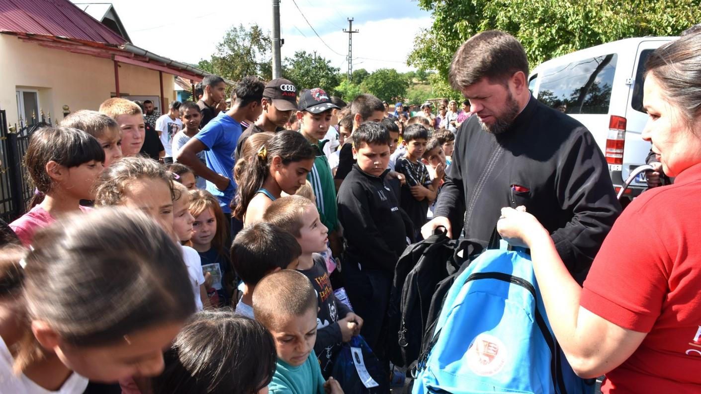 Programul eparhial „Un ghiozdan pentru noul an școlar” / Foto: episcopiahusilor.ro copii primind rechizite