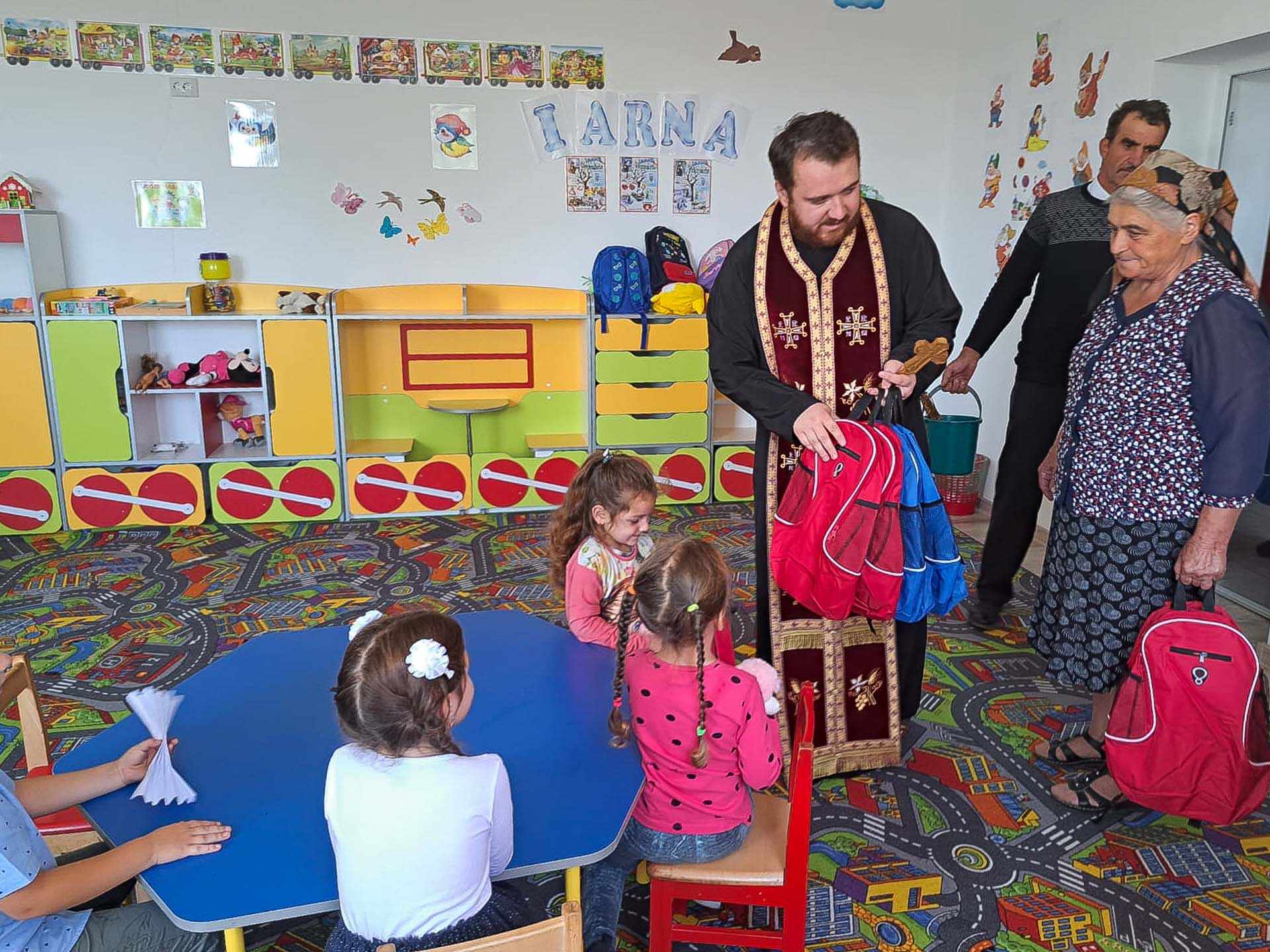 Preot, împărțind rechizite