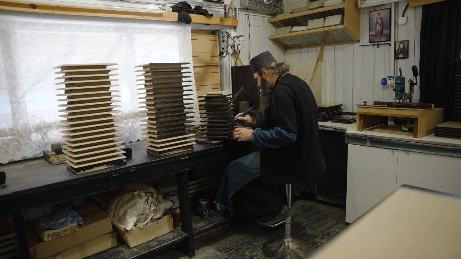 Părintele Ghelasie vopsind marginea blatului de lemn