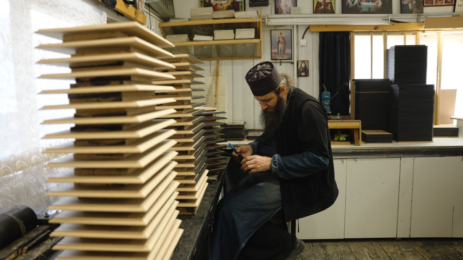 Părintele Ghelasie vopsind marginile blaturilor de lemn