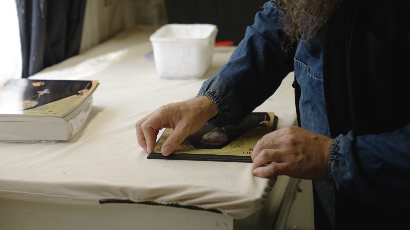 Părintele Ghelasie lipind o icoană pe blatul de lemn