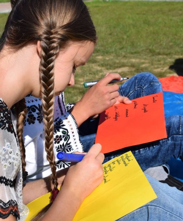 Fată scriind cuvinte în limba română pe o hârtie