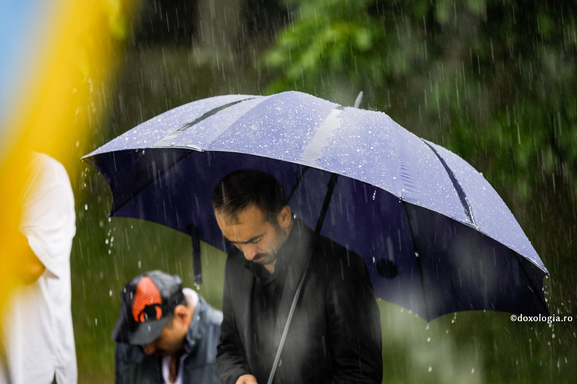 bărbat stând sub umbrelă în ploaie