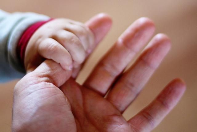 bebeluș ținând un deget în mână