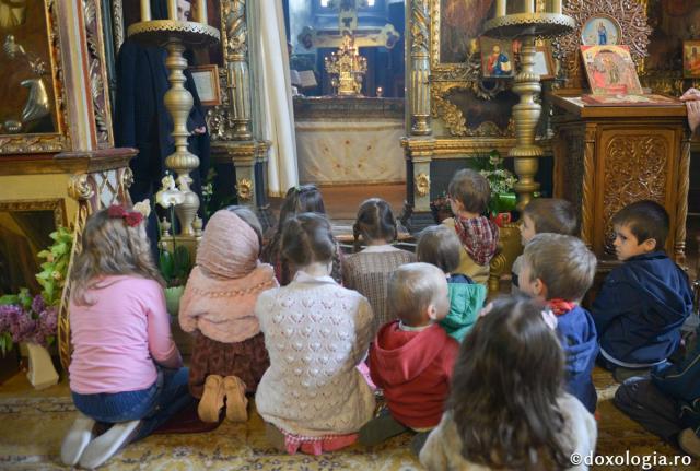 copii stând în genunchi în biserică