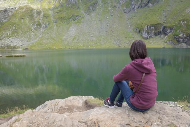 tânără stând pe marginea lacului