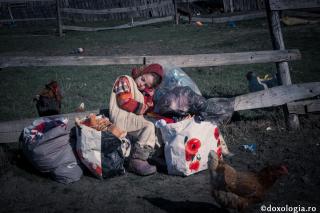 fetiță stând între sacoșe încărcate