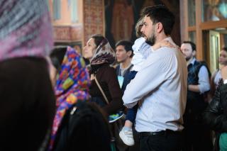 tată cu copilul în brațe în biserică