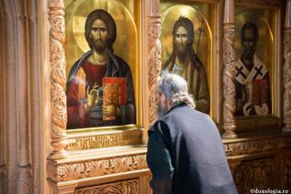 călugăr închinându-se la icoana Mântuitorului