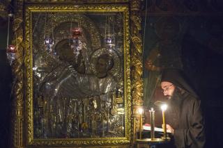 călugăr lângă icoana Maicii Domnului