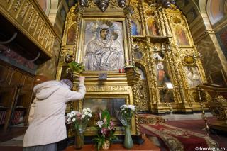 femeie în genunchi în fața icoanei Maicii Domnului