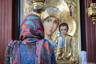 femeie în fața icoanei Maicii Domnului