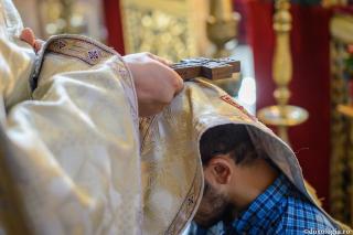 preot ținând crucea peste capul unui credincios