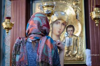 femeie în fața icoanei Maicii Domnului