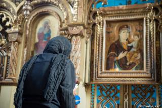 femeie rugându-se în fața icoanei Maicii Domnului