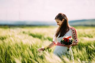 femeie cu buchet de flori în mână în lan