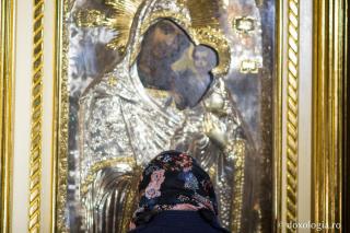 femeie în fața icoanei Maicii Domnului