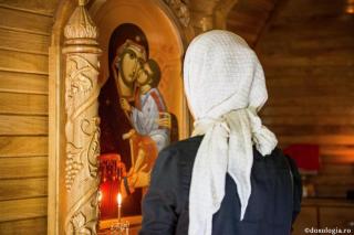 femeie în fața icoanei Maicii Domnului