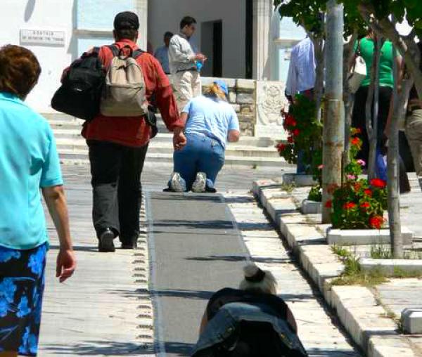 Pelerini urcând în genunchi scările din port până la biserica Maicii Domnului din Tinos