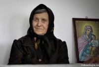 bătrână lângă icoana Maicii Domnului
