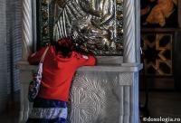 femeie în fața icoanei Maicii Domnului