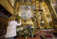 femeie în genunchi în fața icoanei Maicii Domnului