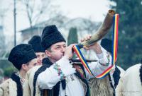 bărbat în costum popular suflând în corn
