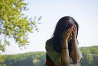 tânără acoperindu-și fața cu mâinile