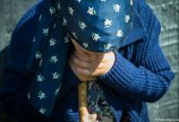 femeie bătrână stând cu capul plecat