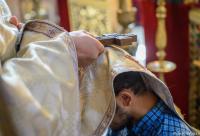 preot cu crucea în mână pe capul unui credincios