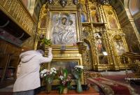 femeie în fața icoanei Maicii Domnului