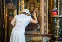 femeie cu pălărie rugându-se la icoana Maicii Domnului