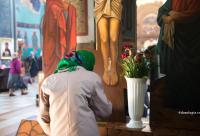 femeie închinându-se în fața Sfintei Cruci