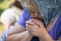 femeie rugându-se cu mâinile la gură