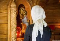 femeie în fața icoanei Maicii Domnului