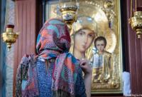 femeie în fața icoanei Maicii Domnului