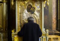 bărbat în fața icoanei Maicii Domnului